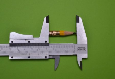 Ein Bleistift klemmt zwischen den Backen eines Messschiebers