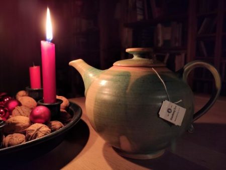 Bild zur Weihnachtsgeschichte: eine Teekanne neben einer brennenden Kerze am Adventskranz